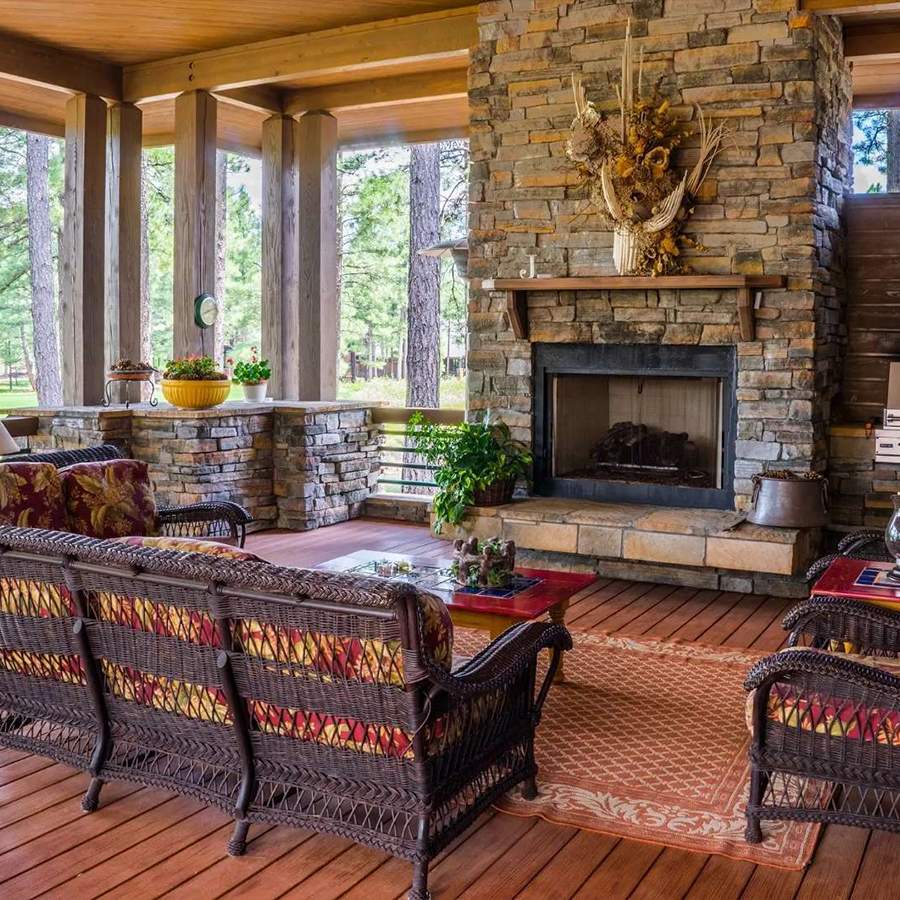 a patio with a stone fireplace and chairs
